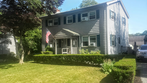 A charming two-story home featuring an American flag and a well-maintained garden.