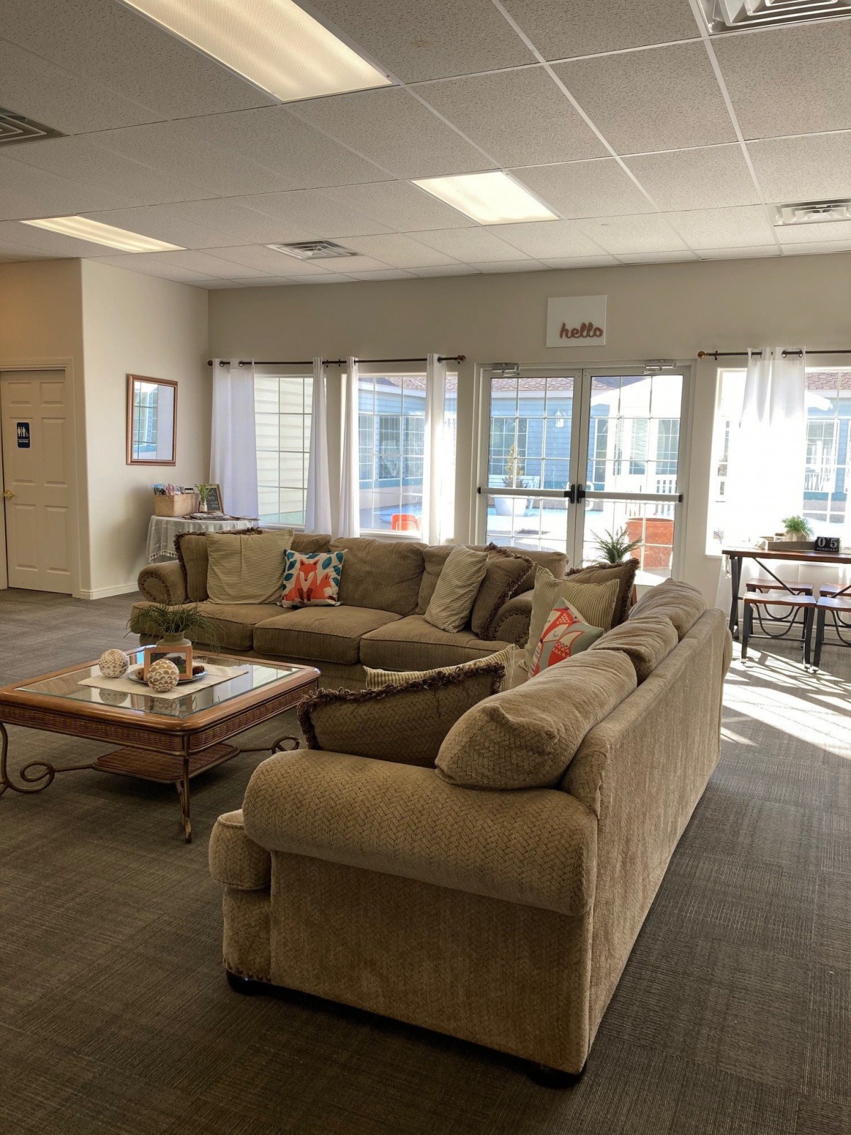 A cozy living room with comfortable couches and a coffee table, sunlit through large windows.