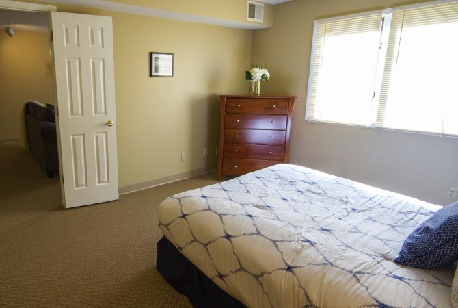 A minimalist bedroom with a bed, dresser, and window.