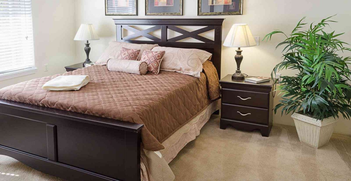 A cozy bedroom with a neatly made bed, nightstands, and lamps.