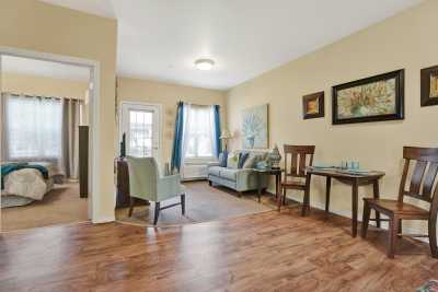 A cozy living room with wood flooring, featuring a sofa, armchairs, and wall art.