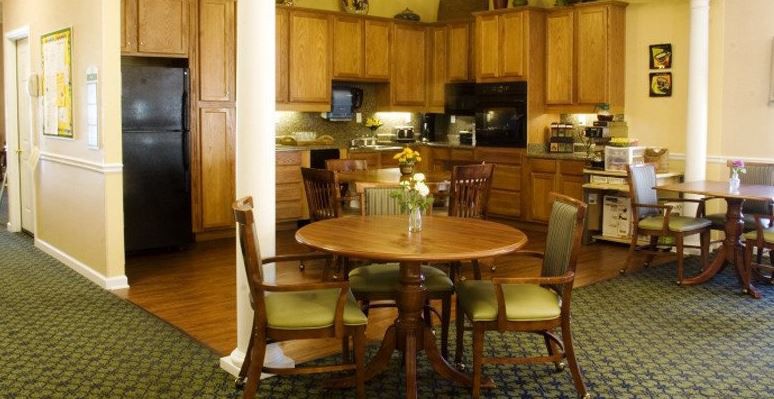 A cozy kitchen and dining area with wooden cabinets, a round table, and chairs.