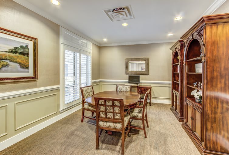 A well-furnished dining room with a round table, chairs, and a wooden bookshelf.