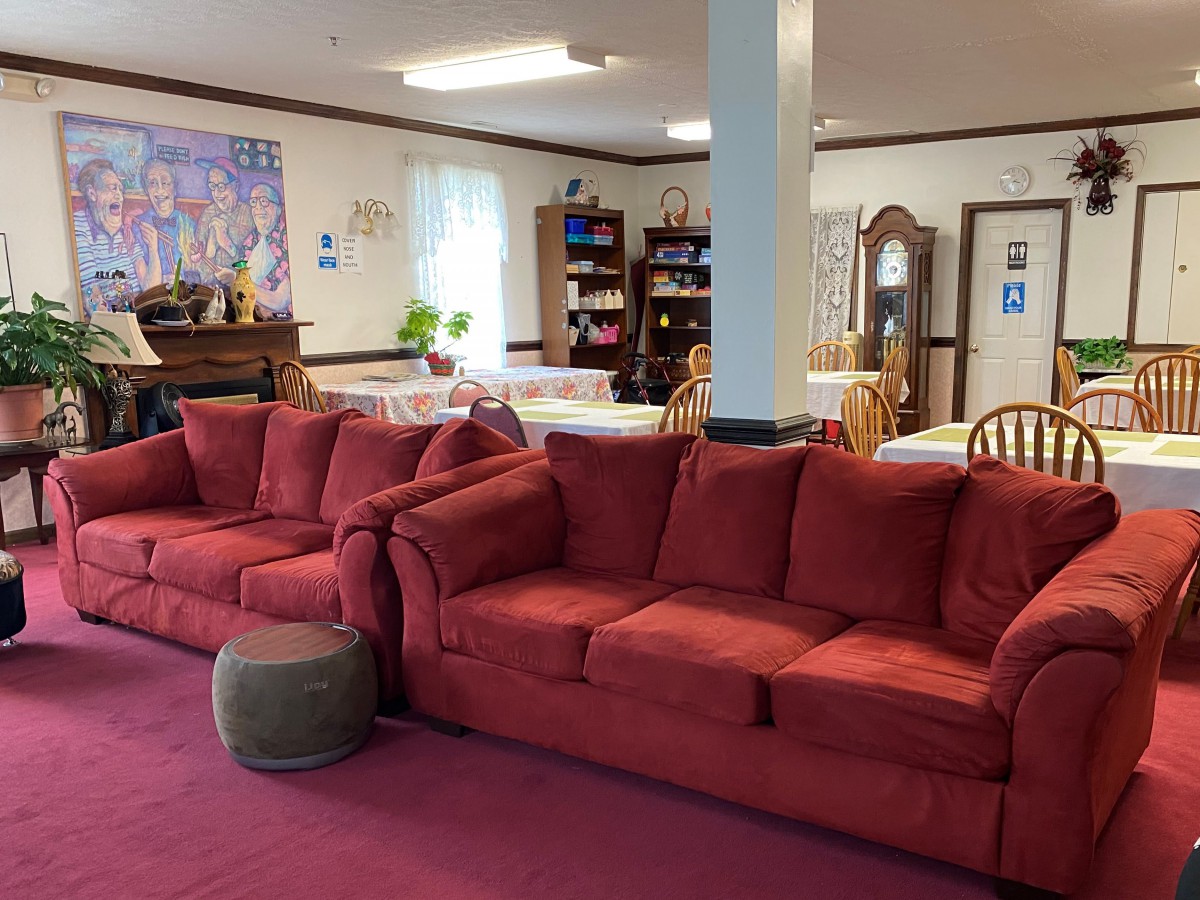 A cozy living room with red sofas, tables, and a bookshelf.