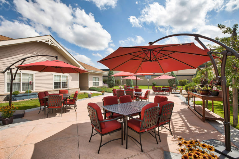 An outdoor patio area with red umbrellas and seating under a cloudy sky.