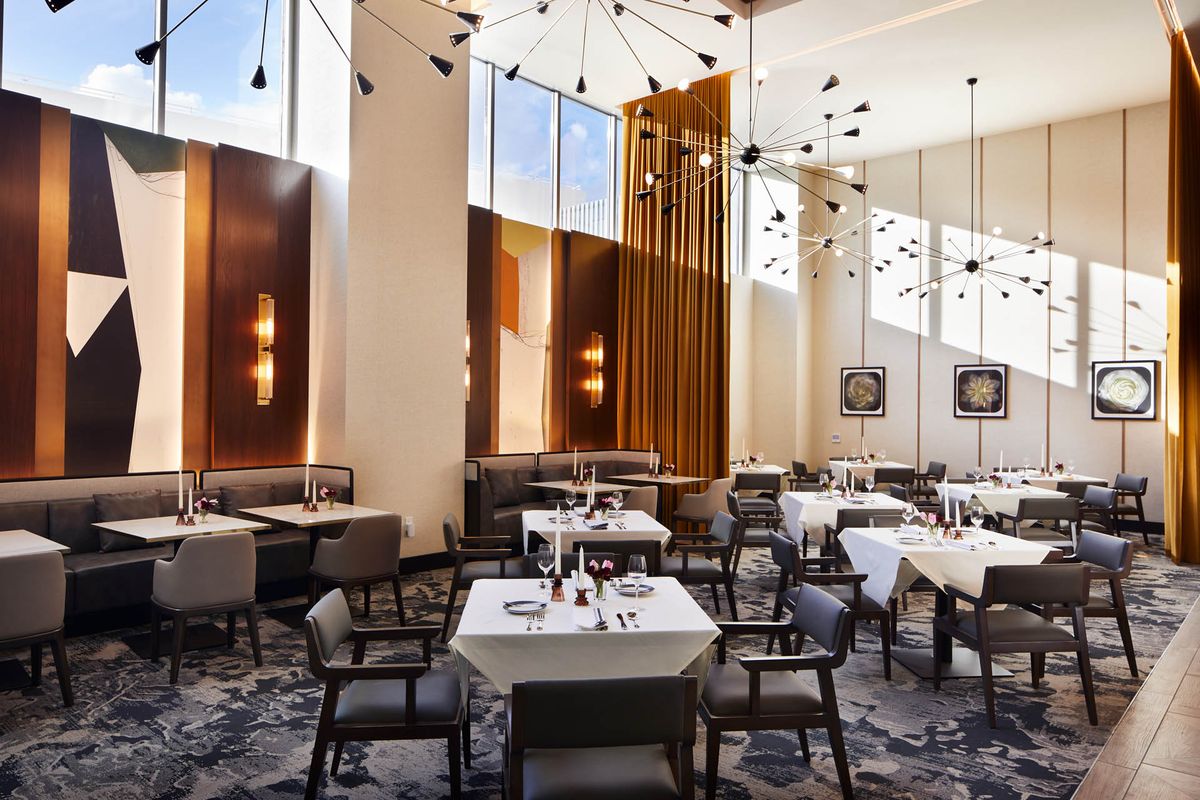 A modern restaurant interior with elegantly set tables and contemporary decor.