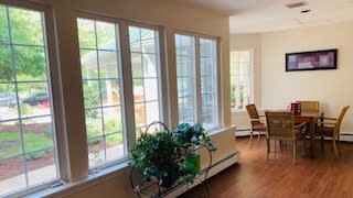 A bright interior space with large windows, plants, and a dining area.
