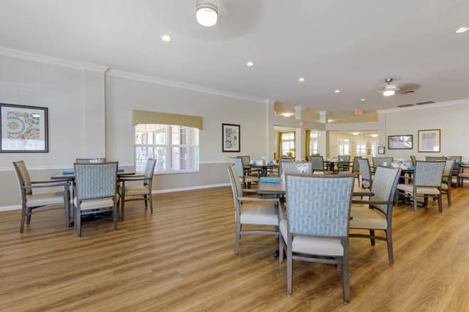 A spacious dining room with neatly arranged tables and chairs on a hardwood floor.