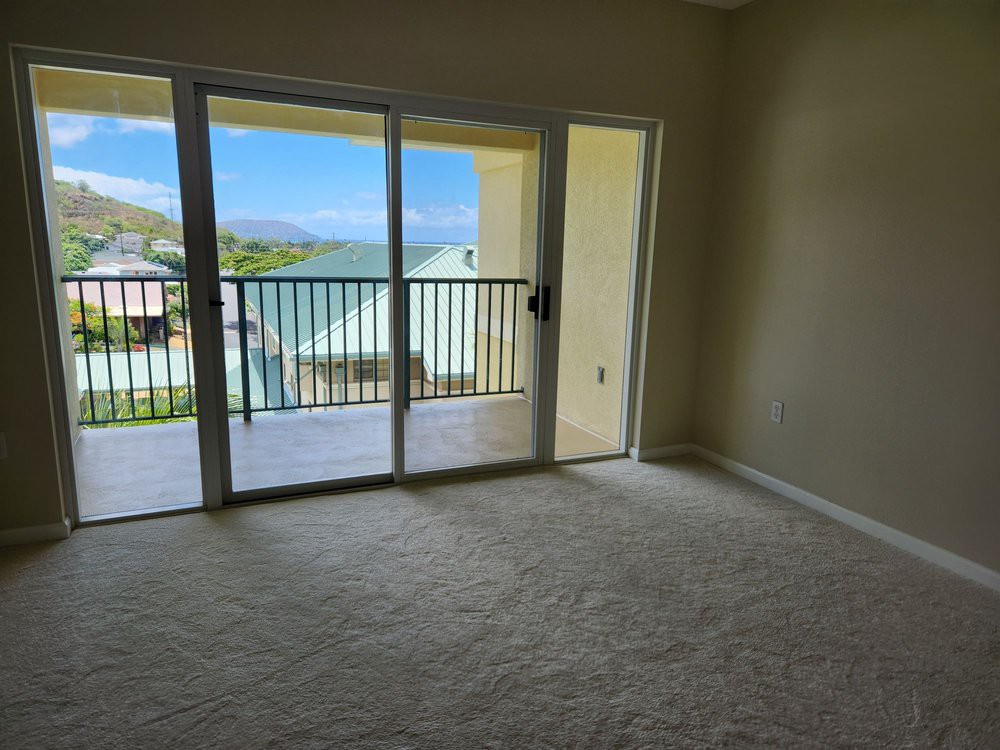 A carpeted room with sliding doors leading to a balcony offering a scenic view.