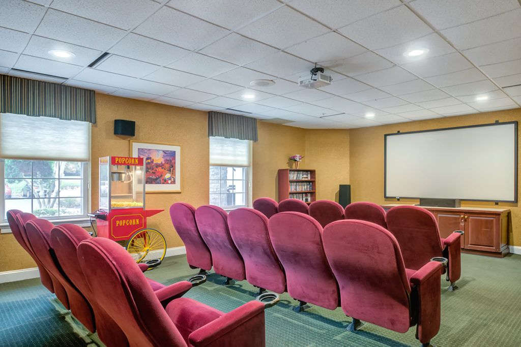 A cozy home theater with red seating and a popcorn machine.