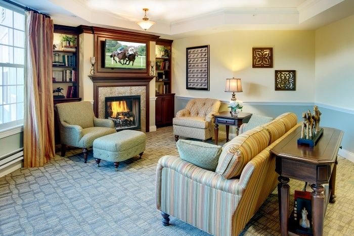 A cozy living room with a fireplace, armchairs, and bookshelves.