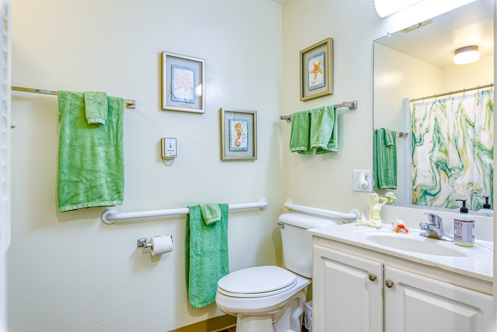 A well-decorated bathroom featuring green towels and framed wall art.