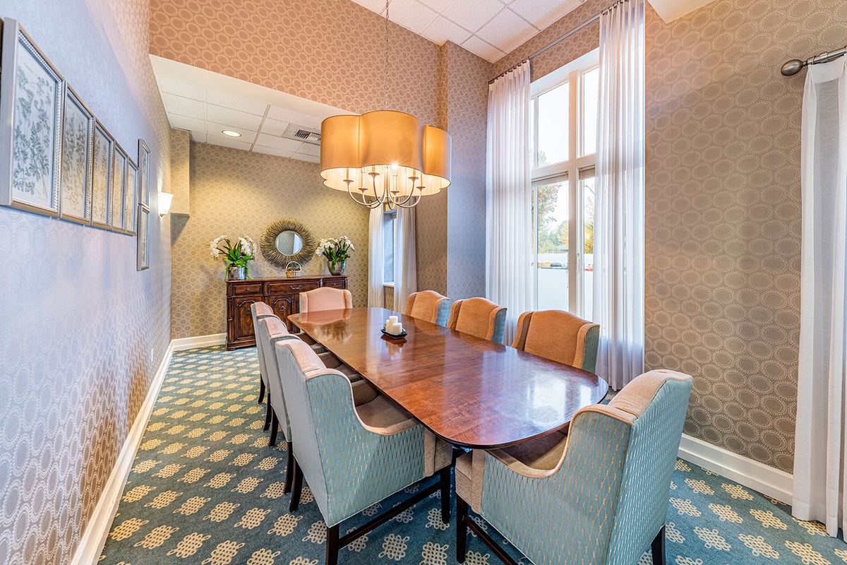 An elegant dining room with a wooden table, upholstered chairs, and a large chandelier.