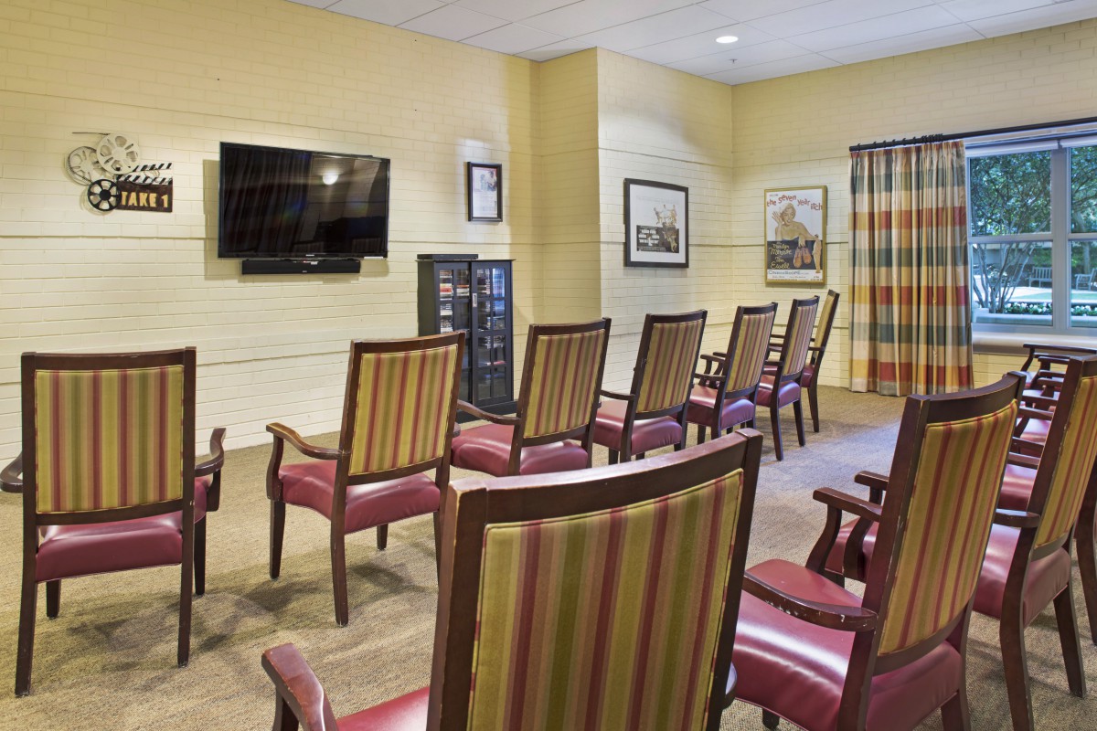A meeting room with arranged chairs facing a television on the wall.
