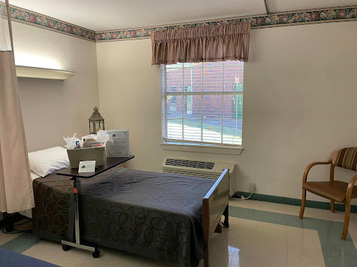 A view of a patient room in a hospital, featuring a bed, window, and basic furnishings.
