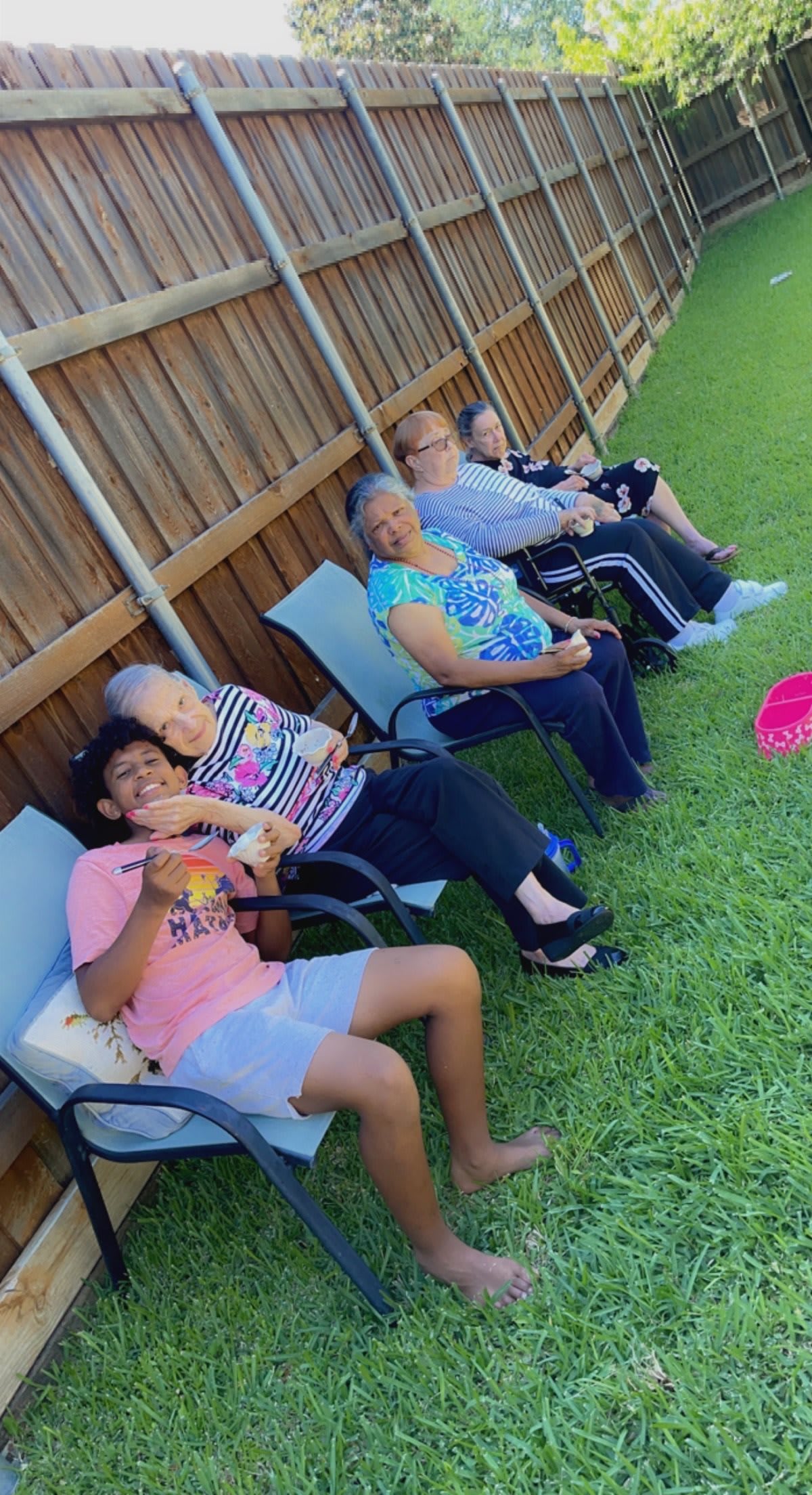 A group of people sitting on lawn chairs, enjoying a sunny day outdoors.