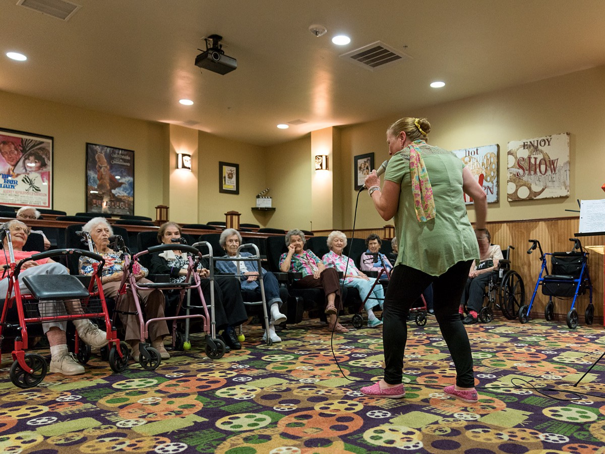 A group of seniors participating in an indoor activity led by an instructor.