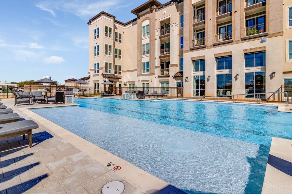 A luxurious apartment complex featuring a large outdoor swimming pool.