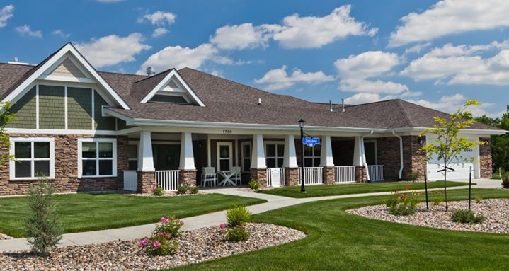 A suburban house with a manicured lawn under a clear blue sky.