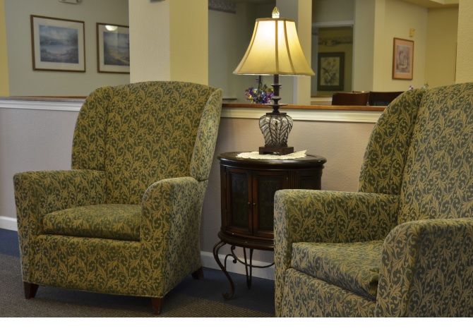 A cozy living room setup with two patterned chairs and a table with a lamp in between.