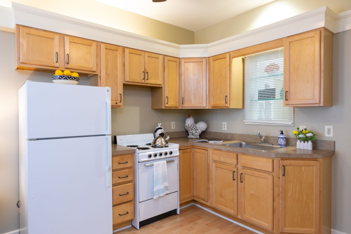 A cozy kitchen with wooden cabinets, a refrigerator, and a stove.