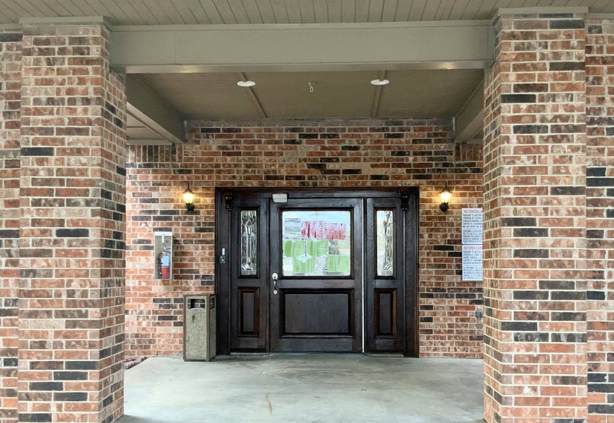 Front entrance of a brick building with double doors and a covered porch.