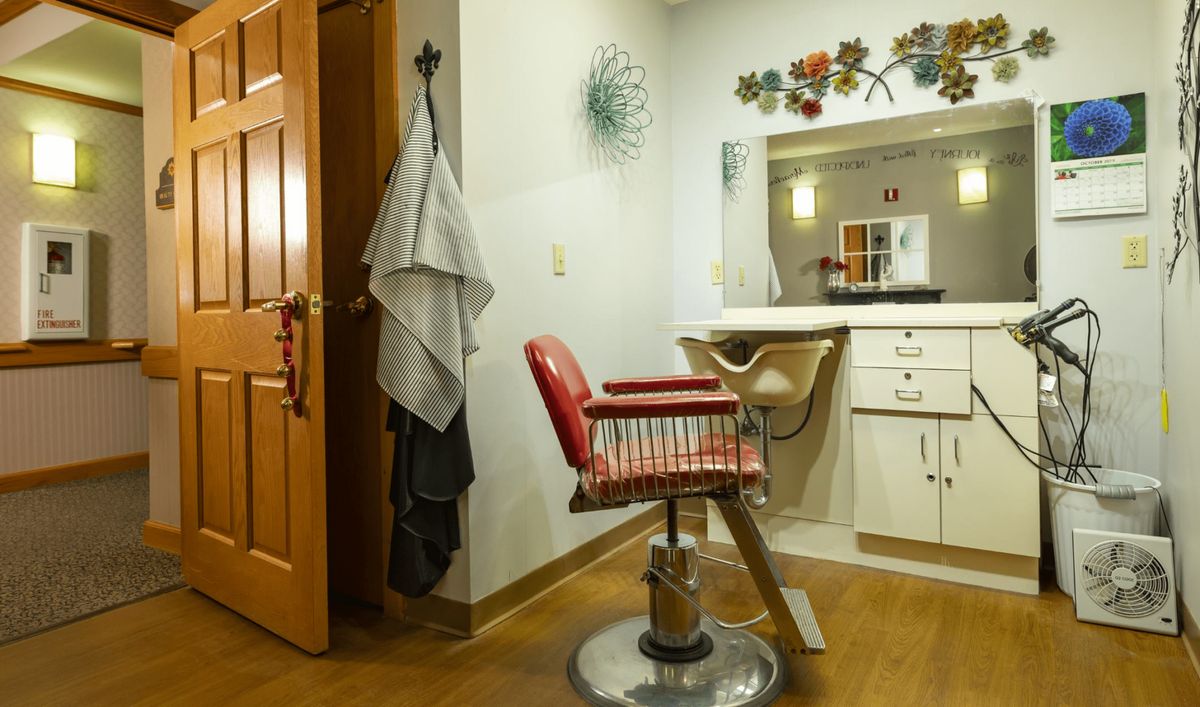 An interior view of a barbershop featuring a classic red barber chair and mirror.