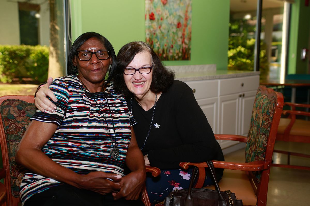 Two friends sitting together indoors, smiling and enjoying each other's company.