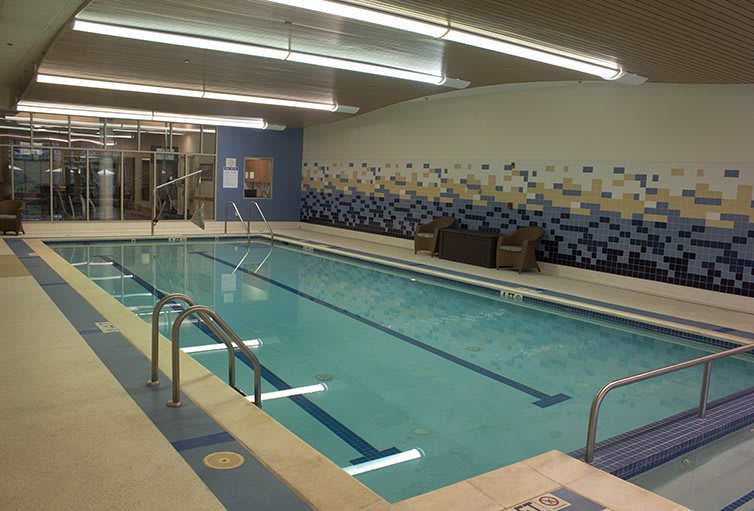An indoor swimming pool with clear water and surrounding lounge chairs.
