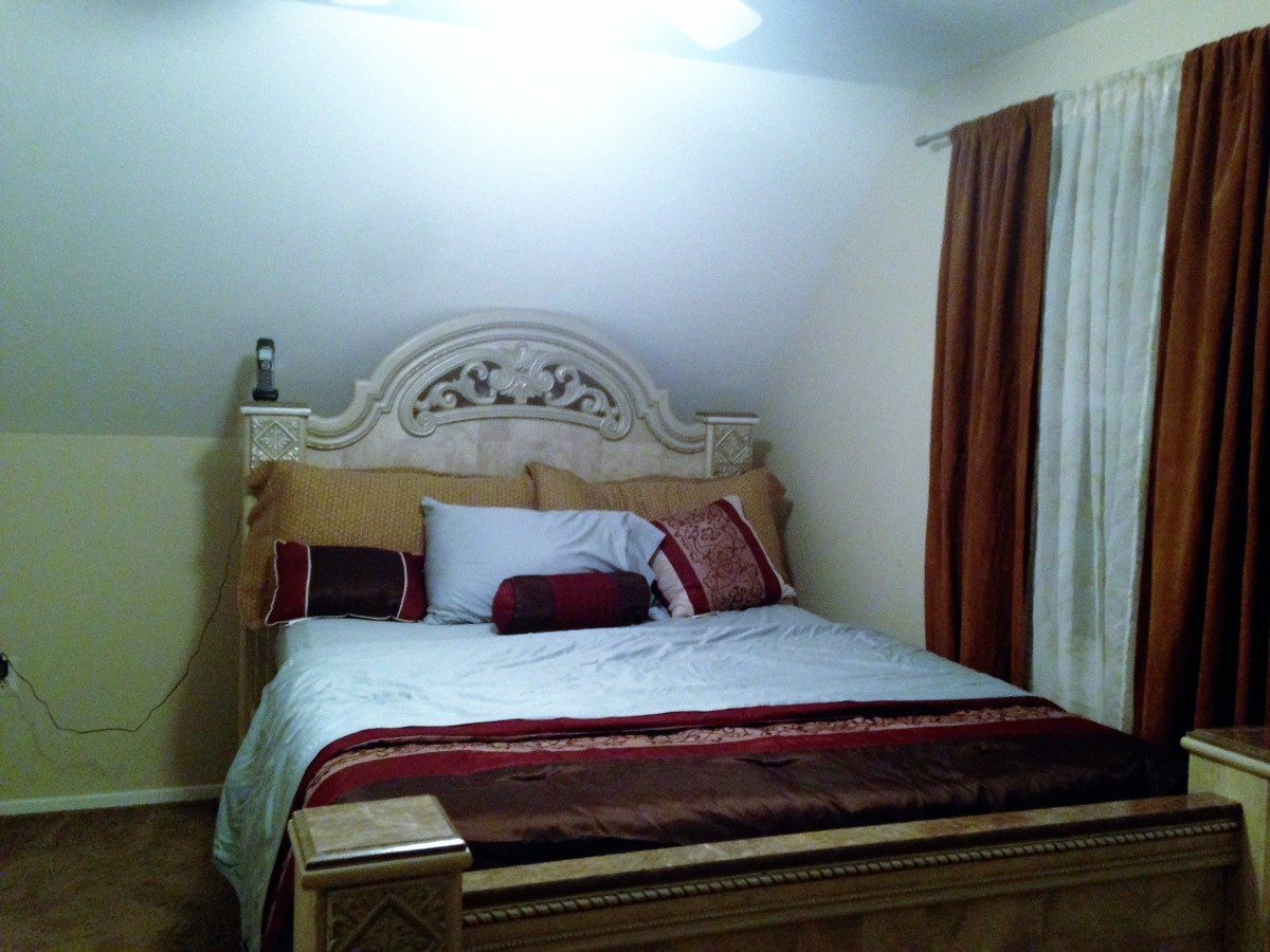 A cozy bedroom with a large decorative bed and elegant curtains.