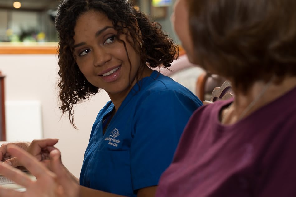 A nurse in blue scrubs conversing with a patient.