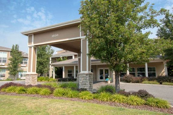 A view of a building entrance with landscaping and trees.