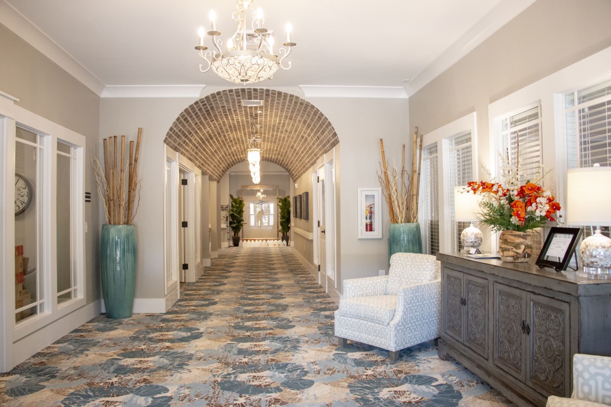 A well-decorated hallway with a chandelier, patterned carpet, and elegant decor.