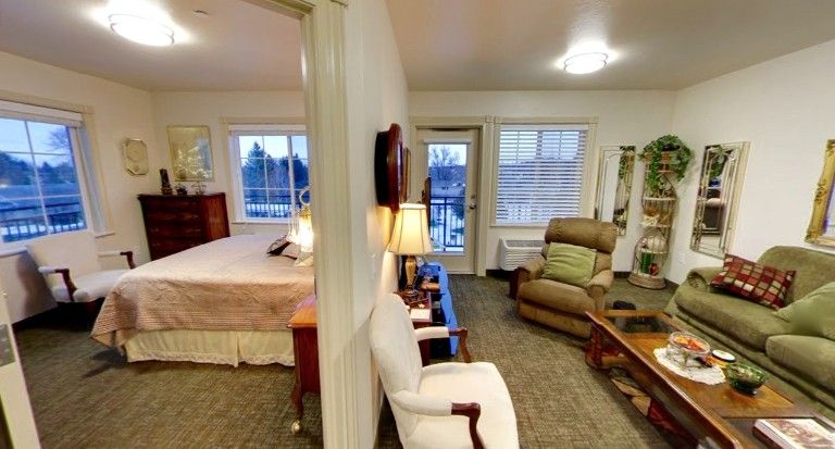 A cozy interior view featuring a living area with chairs and a lamp, adjacent to a bedroom.