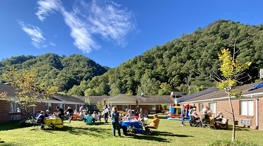 A vibrant outdoor gathering set against a picturesque mountain backdrop, filled with families enjoying activities and each other's company.