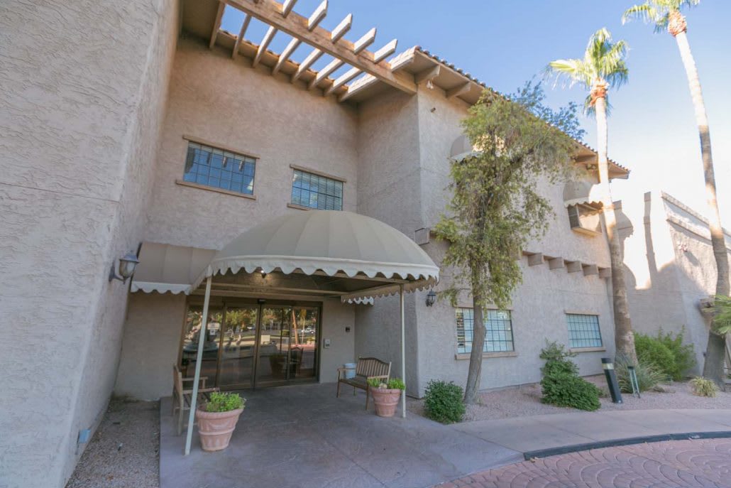 A building entrance with an awning and desert landscaping.