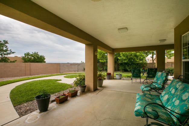 A covered patio with seating and a view of the backyard garden.