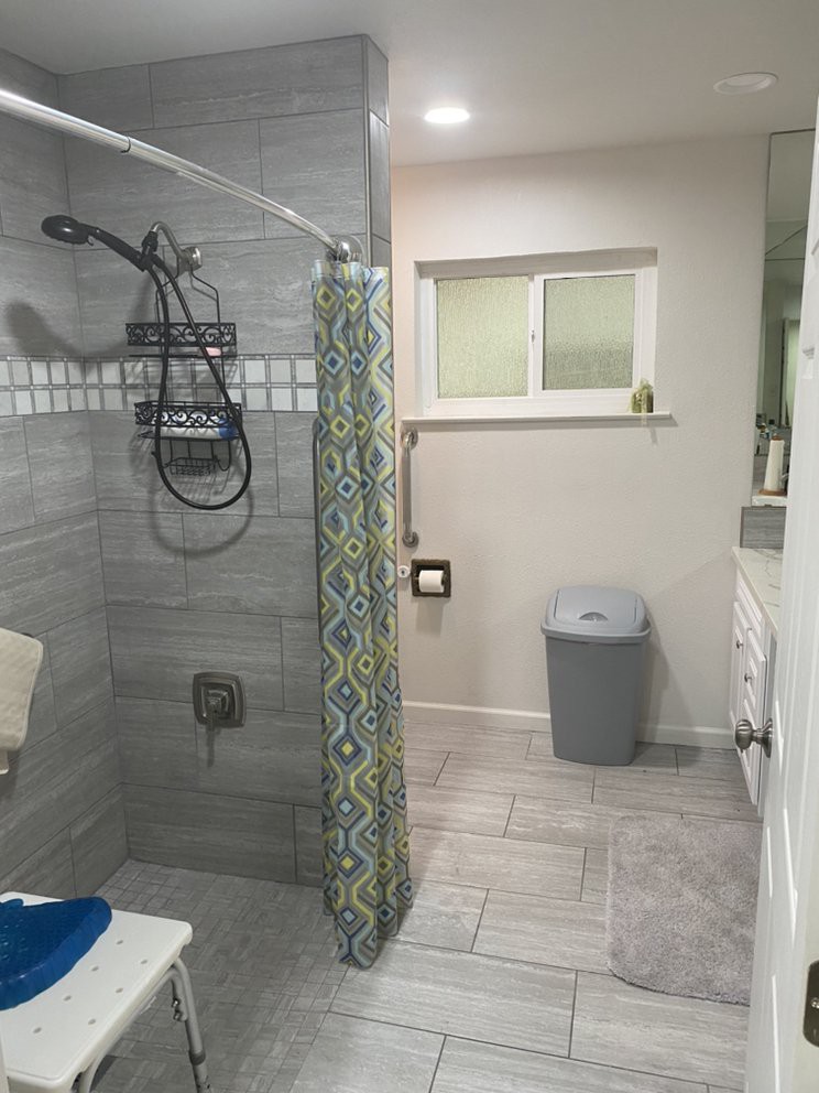 A modern bathroom with a tiled shower area and patterned shower curtain.