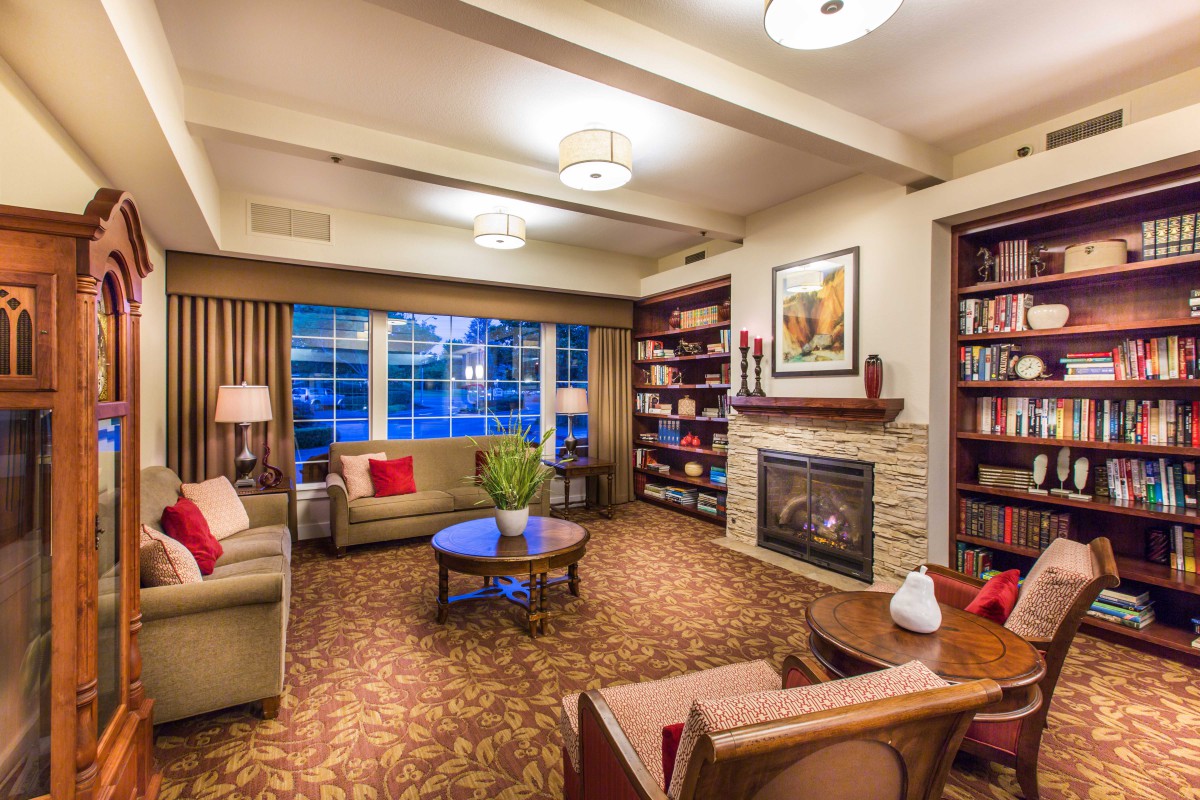 A cozy living room with comfortable seating, a fireplace, and bookshelves.