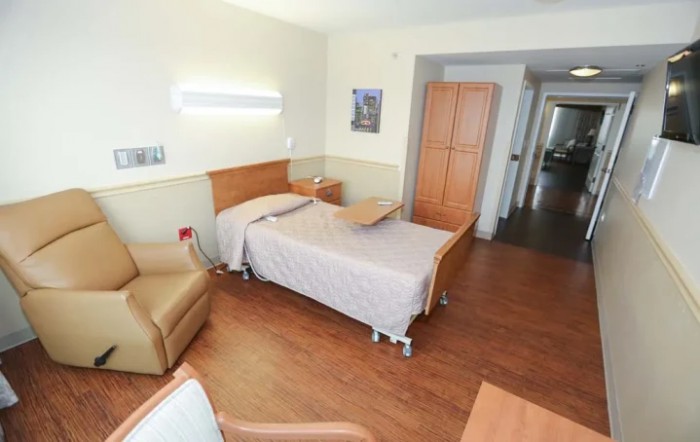 A clean and organized hospital room with a single bed and medical equipment.