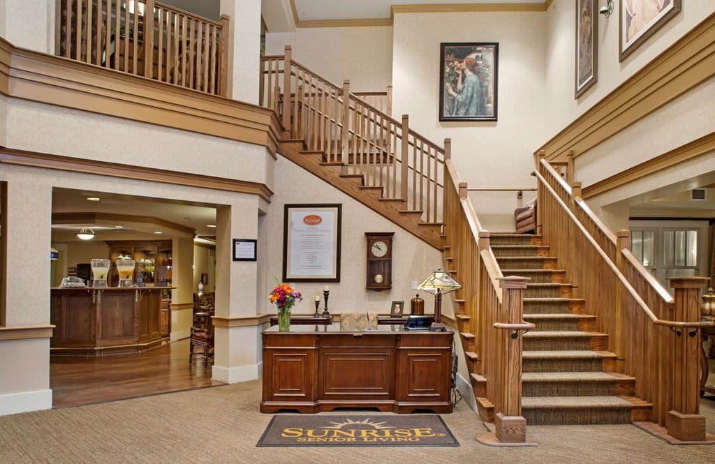 A welcoming hotel lobby featuring a wooden reception desk and staircase.