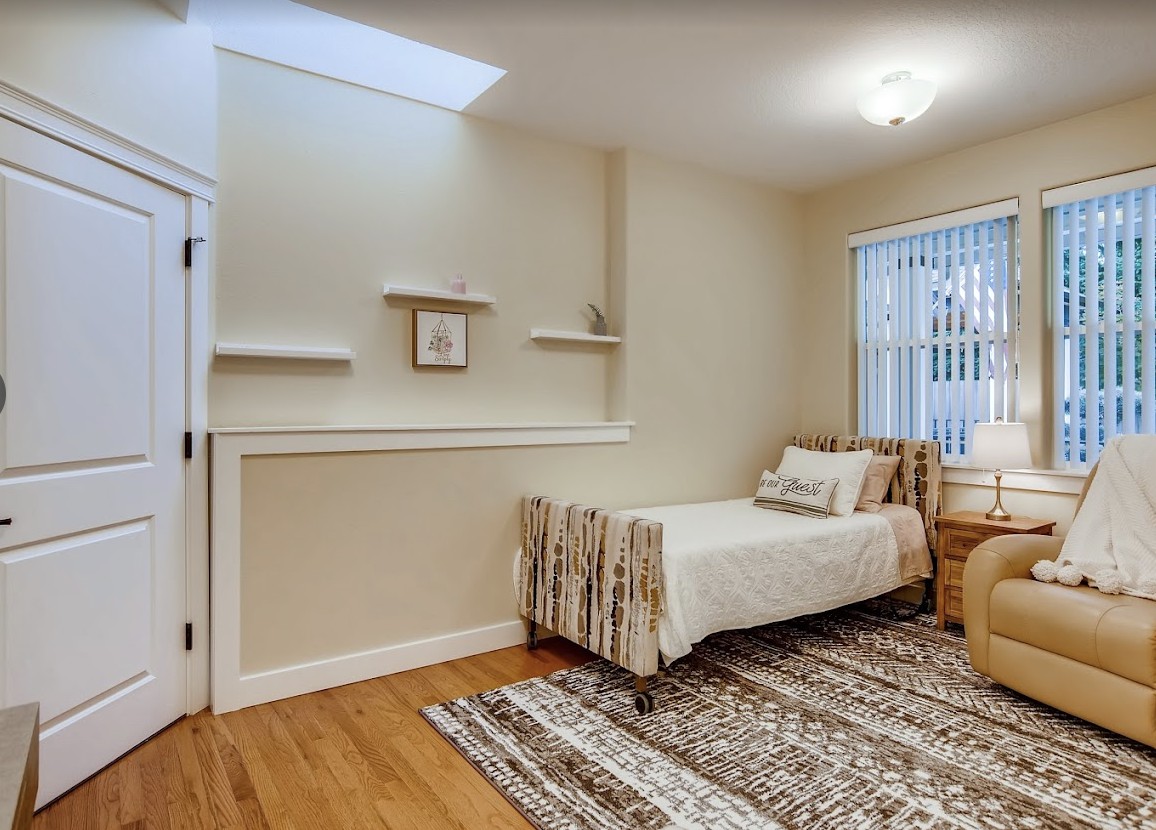 A minimalist bedroom with a single bed, shelves, and a window, featuring neutral colors and a wooden floor.