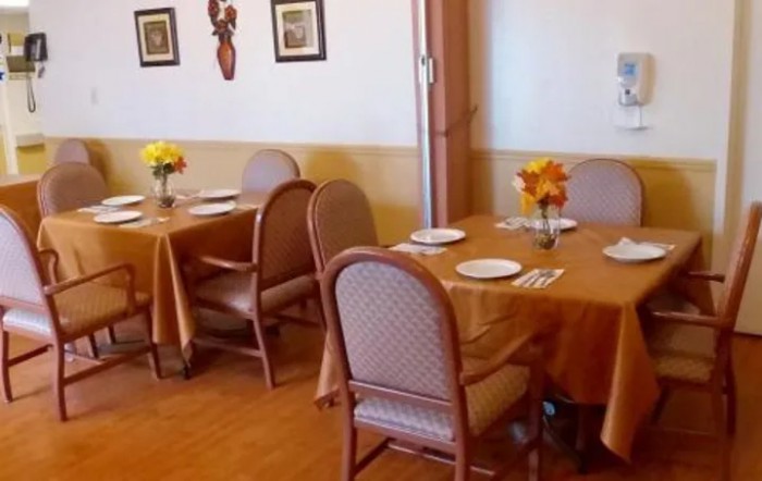 A cozy dining area set with tables, chairs, and floral decorations.