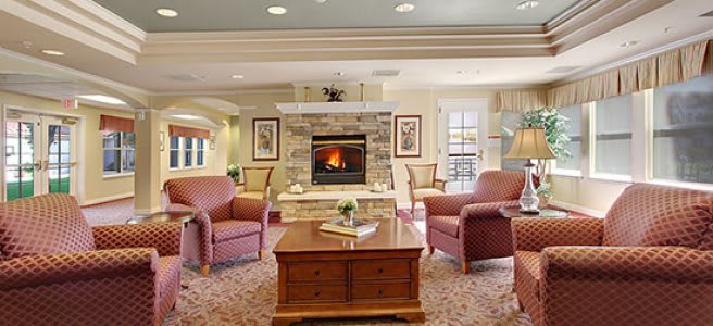 A cozy living room with a central fireplace, surrounded by comfortable armchairs and a wooden coffee table.
