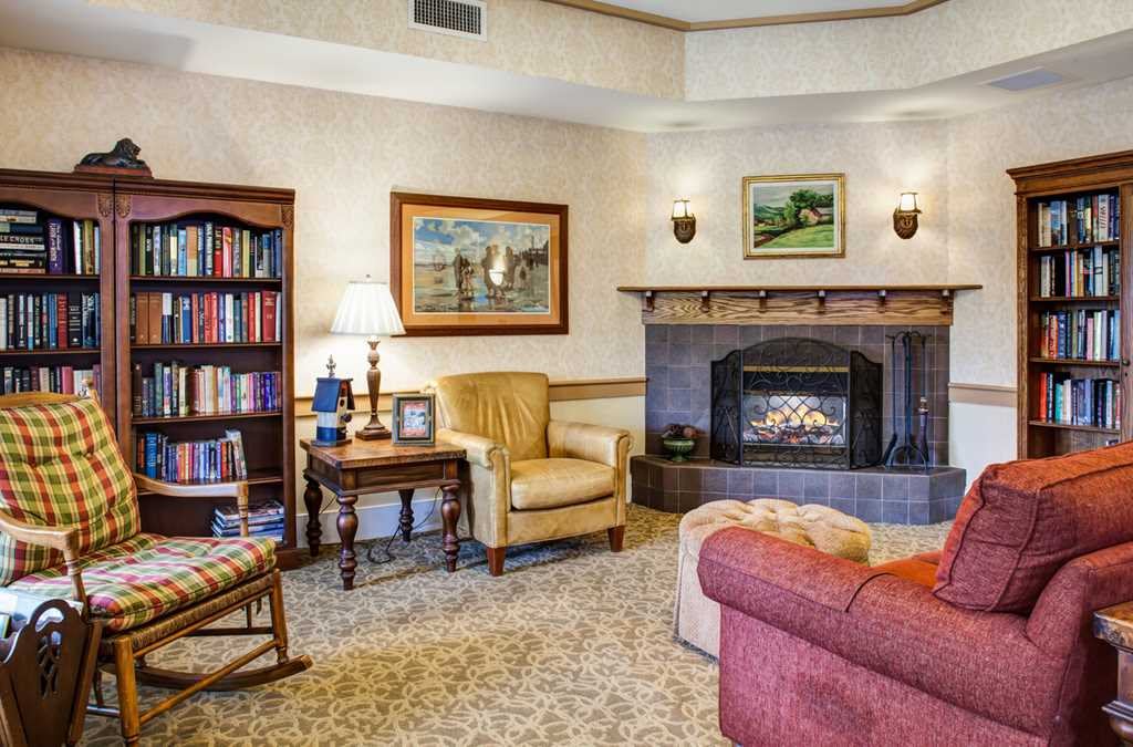 A cozy living room with a fireplace, armchair, and bookshelf.
