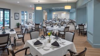 An elegant dining area set up with tables and chairs, each table adorned with formal place settings and decorative napkins.