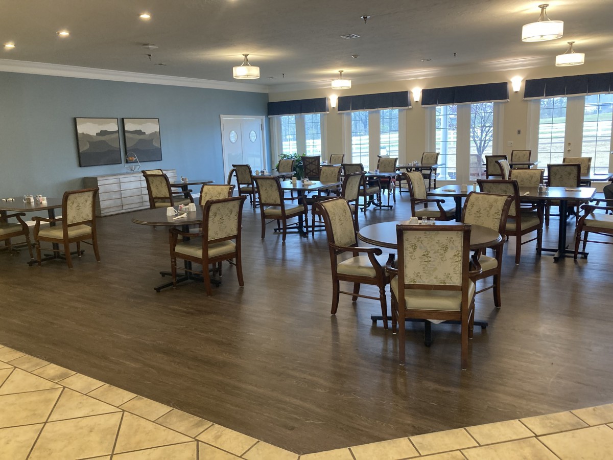 A spacious and well-lit dining room with multiple tables and chairs, featuring modern decor.