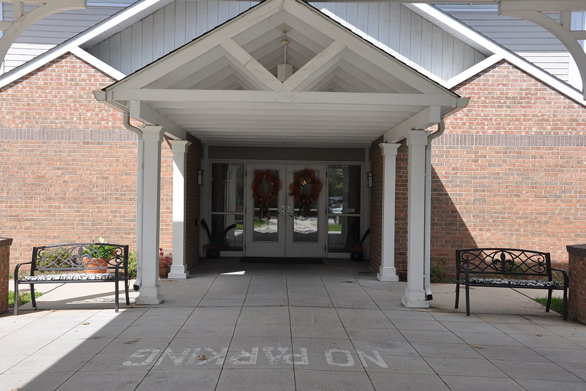 Entrance to a building with an awning and columns, featuring a 'No Parking' sign on the pavement.