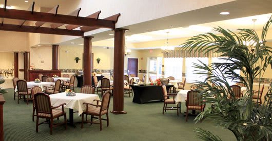 A spacious dining area with neatly arranged tables and chairs, featuring elegant lighting and decor.