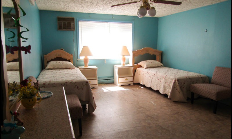 A cozy bedroom with two twin beds, nightstands, and a ceiling fan.